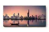 Sinus Art Wandbild 120x80cm Städtische Skyline in der Dämmerung mit reflektierendem Wasser und ruhigem Boot – kontrastreich und elegant