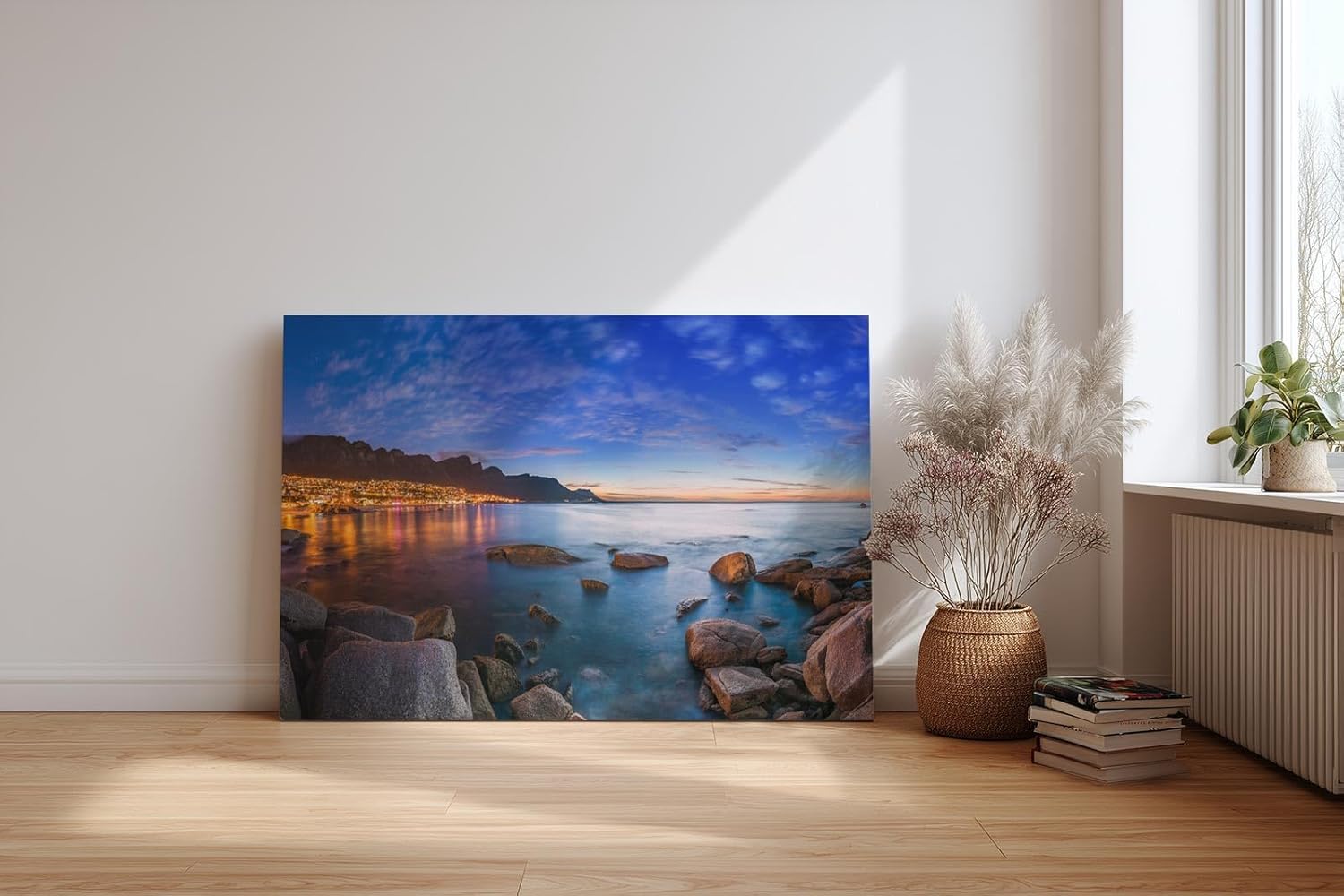 Sinus Art Wandbild 120x80cm Abendliche Szene mit beleuchteter Stadt am Meer, umgeben von Felsen und ruhigem Wasser