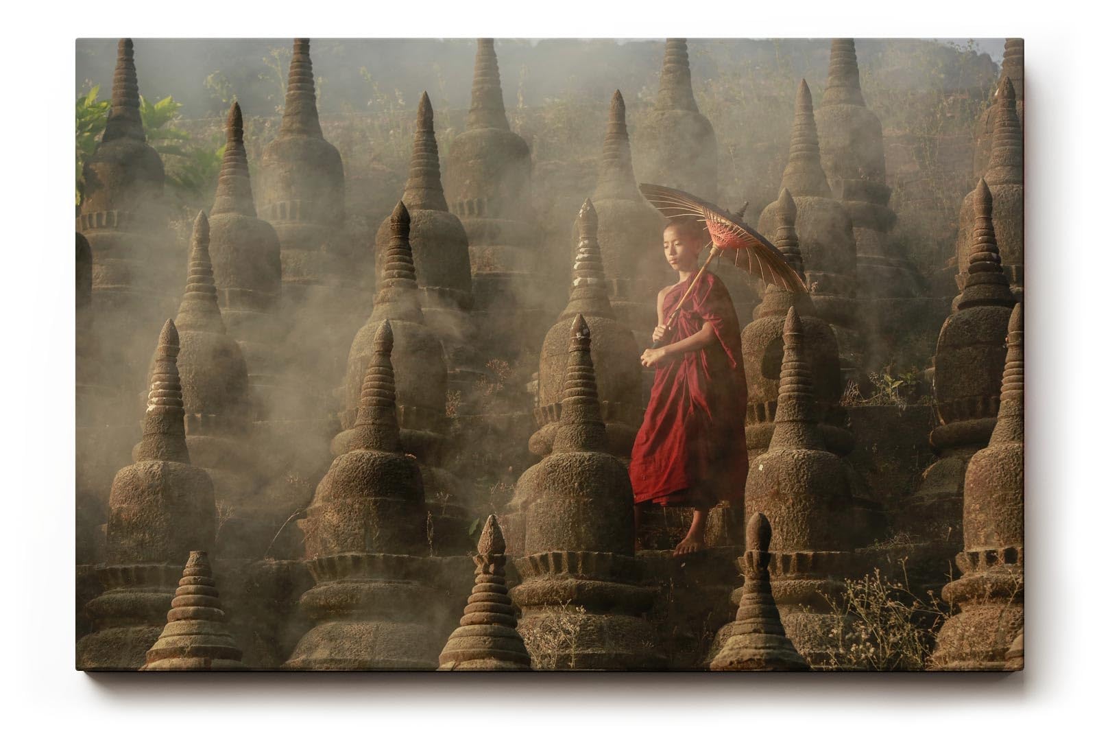 Sinus Art Wandbild 120x80cm Junger Mönch mit Schirm zwischen alten Stupas – Symbol für Glaube und Einkehr