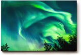Sinus Art Wandbild 120x80cm Atemberaubende Aurora Borealis mit dynamischem Farbspiel über Silhouetten dunkler Bäume