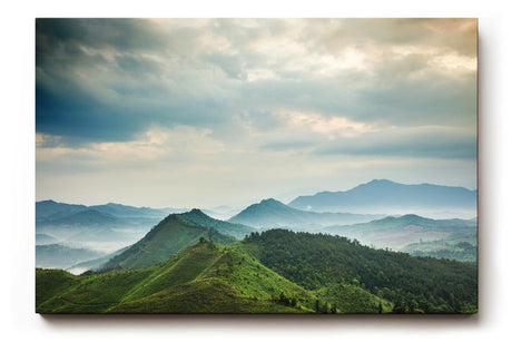 Sinus Art Wandbild 120x80cm Weite grüne Hügel und Berge unter wolkenverhangenem Himmel mit Lichteinfall