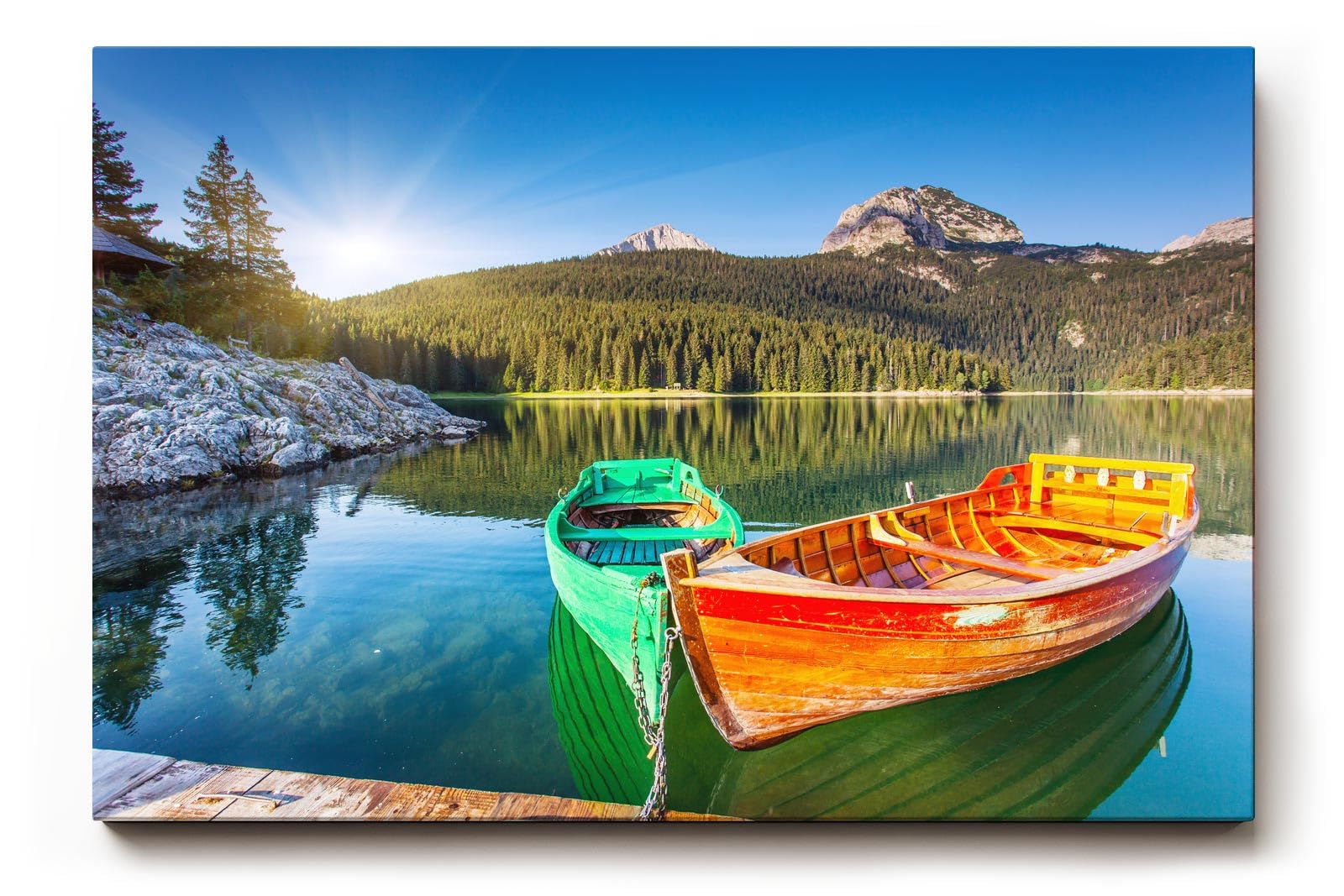 Sinus Art Wandbild 120x80cm Farbkräftige Boote auf spiegelndem Wasser mit Wald und Bergen im Hintergrund