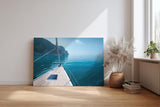 Sinus Art Wandbild 120x80cm Ruhiger Ausblick von einem Segelboot über das glitzernde Wasser zur felsigen Küste