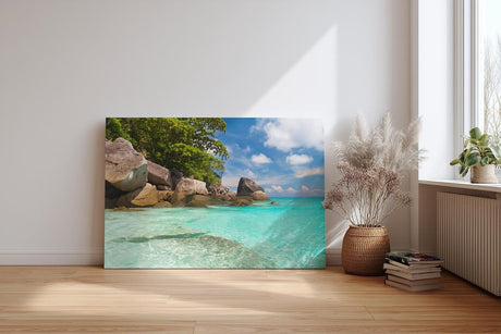 Sinus Art Wandbild 120x80cm Feinsandiger Strand mit Felsen und türkisfarbenem Wasser – paradiesisch und entspannend