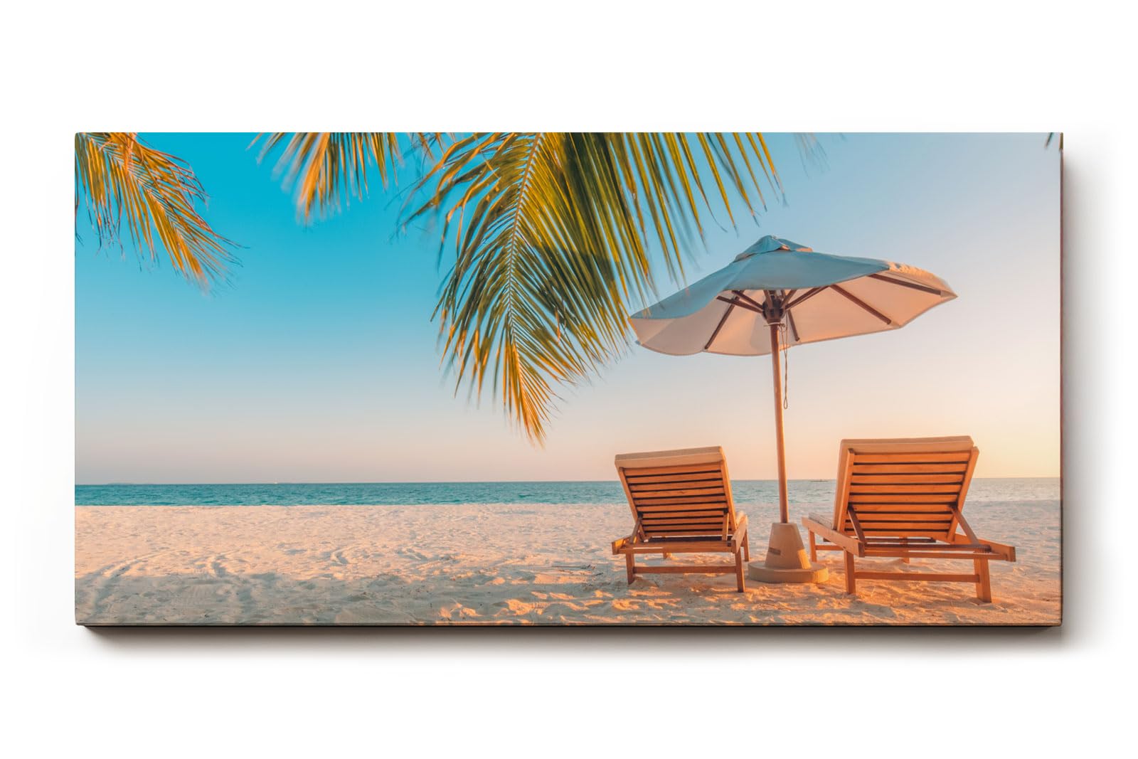 Sinus Art Wandbild 120x80cm Zwei Sonnenliegen am Palmenstrand mit Schirm vor blauem Himmel für entspannte Wirkung