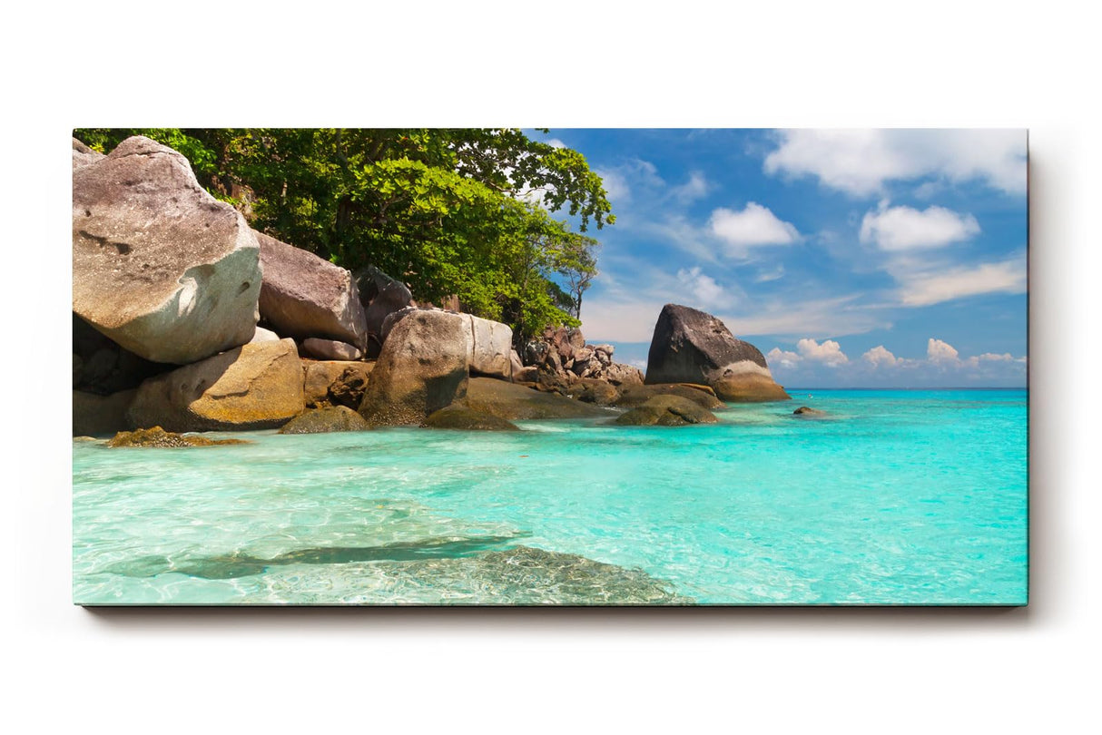 Sinus Art Wandbild 120x80cm Feinsandiger Strand mit Felsen und türkisfarbenem Wasser – paradiesisch und entspannend