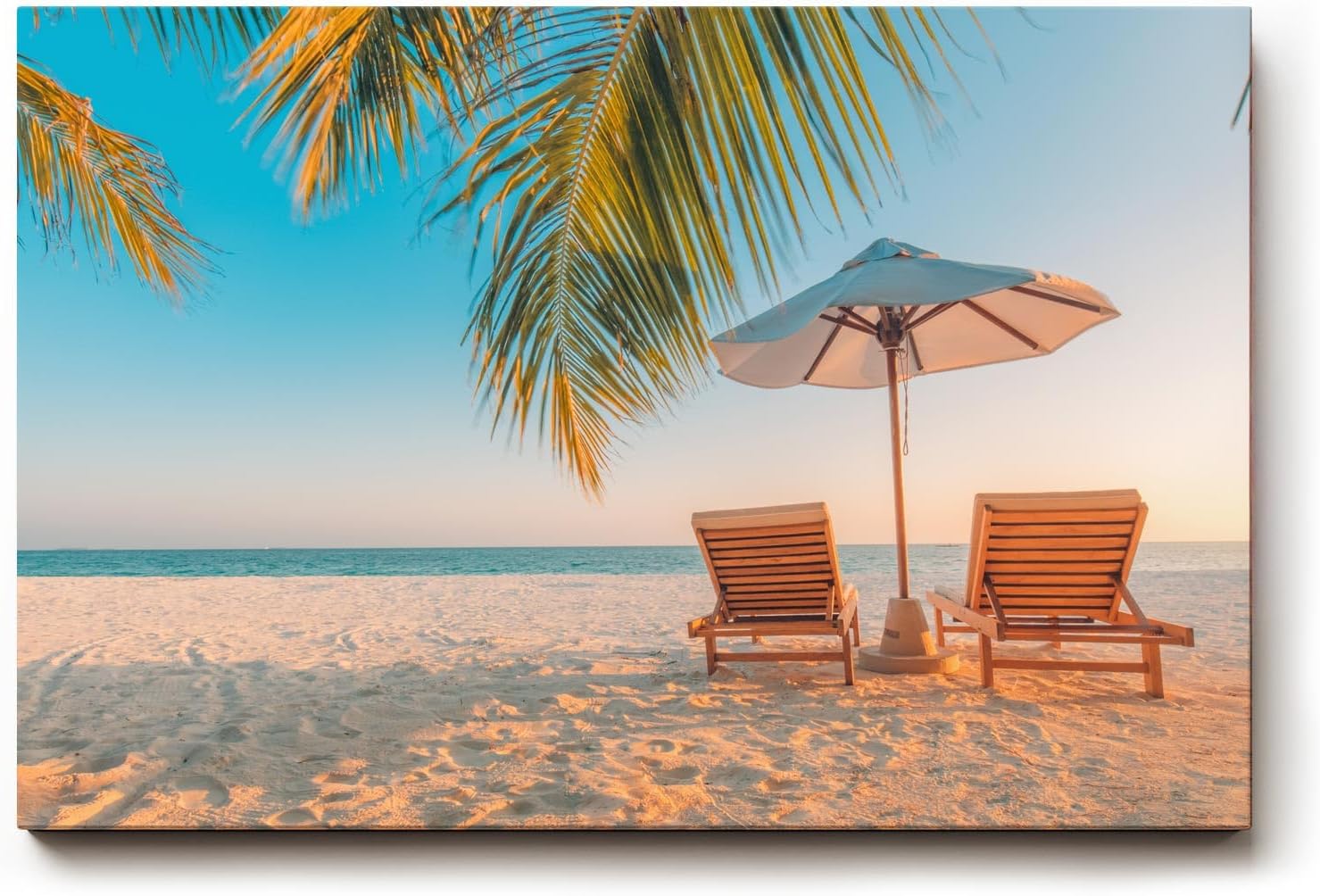 Sinus Art Wandbild 120x80cm Zwei Sonnenliegen am Palmenstrand mit Schirm vor blauem Himmel für entspannte Wirkung