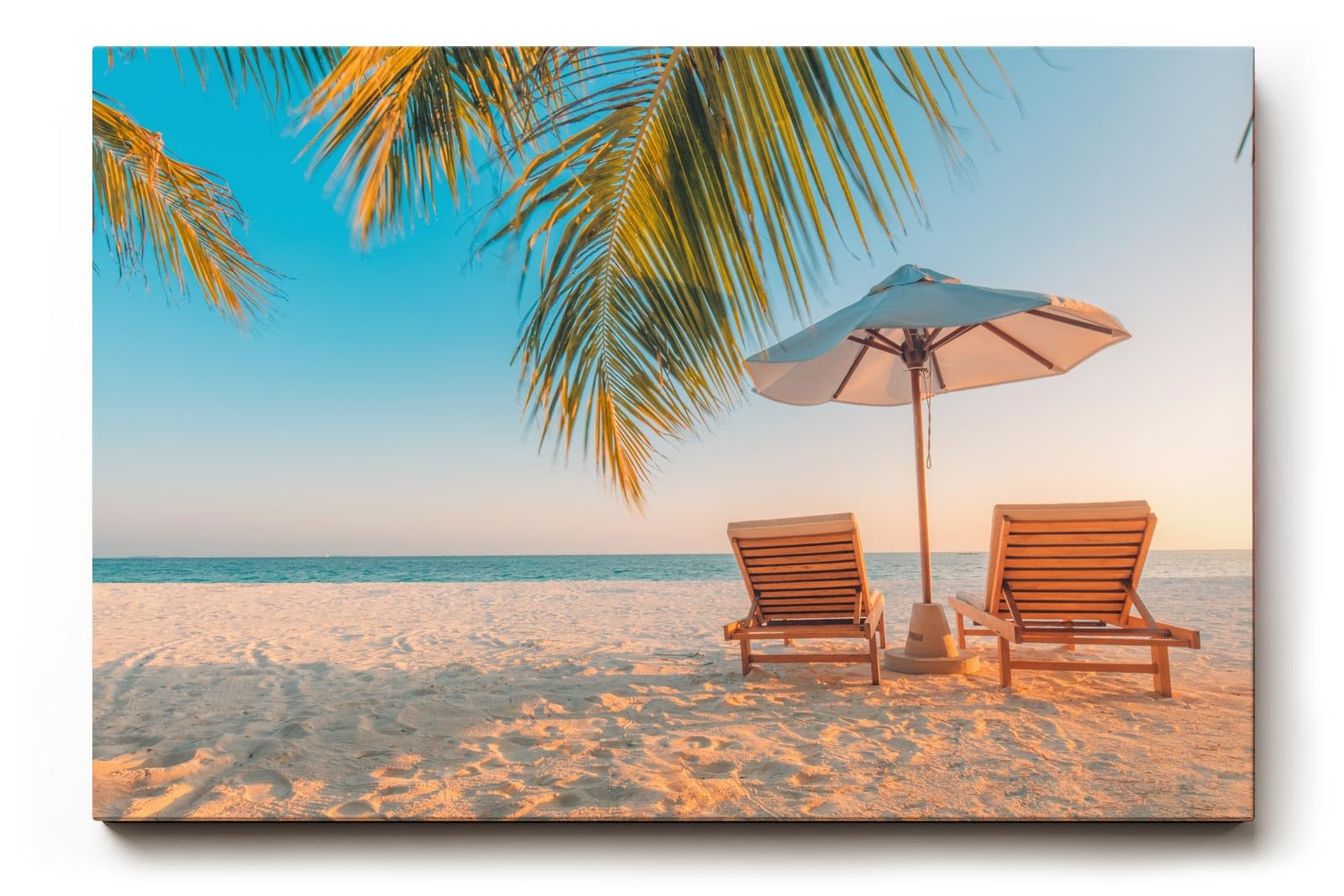 Sinus Art Wandbild 120x80cm Zwei Sonnenliegen am Palmenstrand mit Schirm vor blauem Himmel für entspannte Wirkung