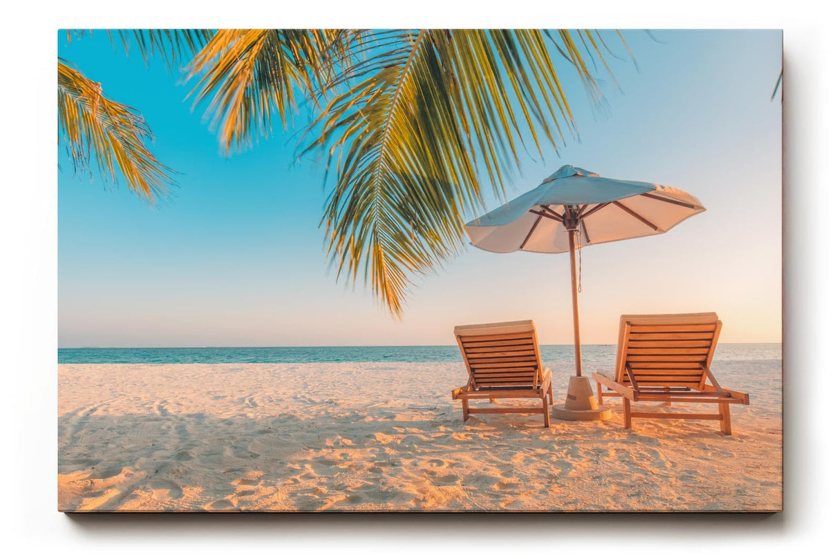 Sinus Art Wandbild 120x80cm Zwei Sonnenliegen am Palmenstrand mit Schirm vor blauem Himmel für entspannte Wirkung