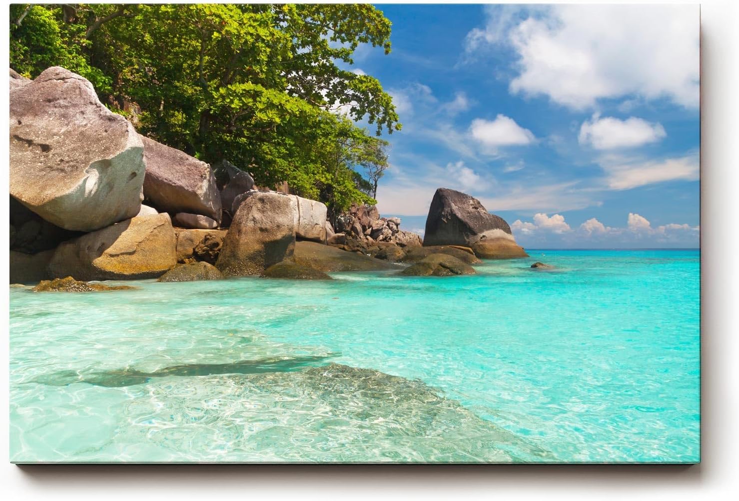 Sinus Art Wandbild 120x80cm Feinsandiger Strand mit Felsen und türkisfarbenem Wasser – paradiesisch und entspannend